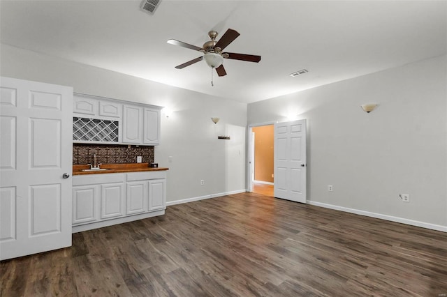 unfurnished living room with indoor wet bar, dark hardwood / wood-style floors, and ceiling fan