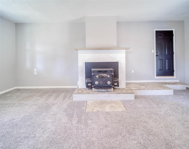 unfurnished living room featuring a textured ceiling, carpet floors, and a wood stove