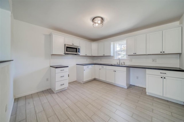 kitchen with decorative backsplash, light wood-type flooring, white cabinetry, and sink