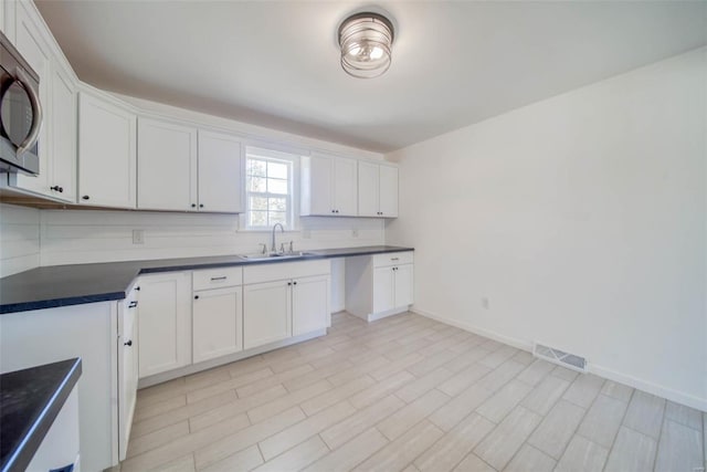 kitchen featuring decorative backsplash, sink, and white cabinets