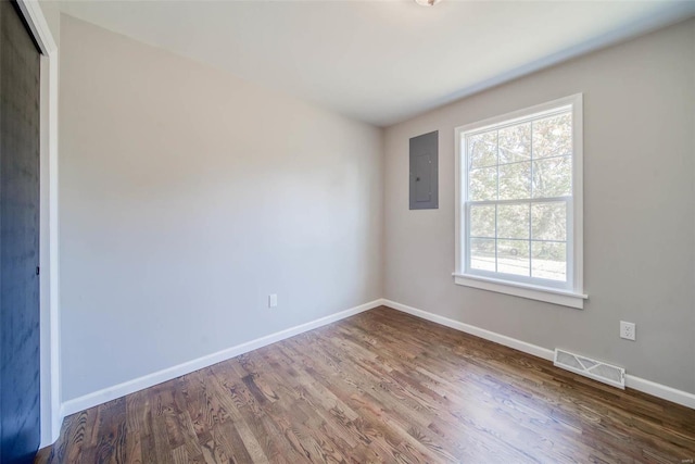 empty room featuring electric panel and dark hardwood / wood-style flooring