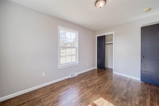 unfurnished bedroom featuring dark hardwood / wood-style floors and a closet