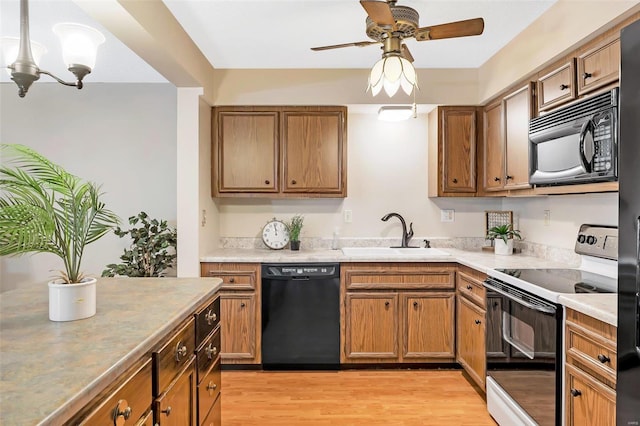 kitchen with ceiling fan with notable chandelier, sink, light hardwood / wood-style floors, and black appliances