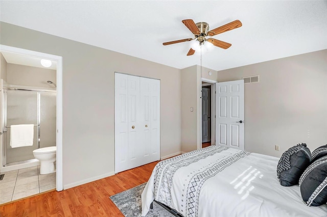 bedroom featuring a closet, light hardwood / wood-style floors, ensuite bath, and ceiling fan