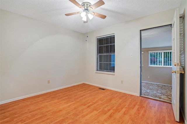 spare room with ceiling fan, light hardwood / wood-style floors, and a textured ceiling