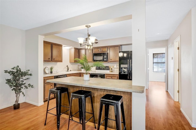 kitchen featuring black appliances, pendant lighting, light wood-type flooring, and a chandelier