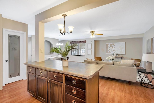 kitchen with ceiling fan with notable chandelier, decorative light fixtures, a kitchen island, and light hardwood / wood-style floors