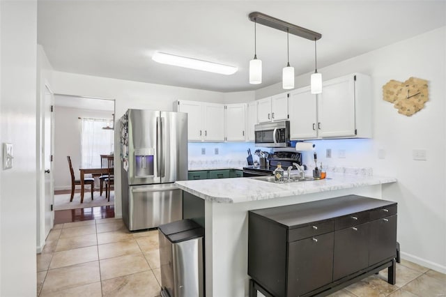 kitchen with kitchen peninsula, white cabinets, hanging light fixtures, appliances with stainless steel finishes, and light tile patterned flooring