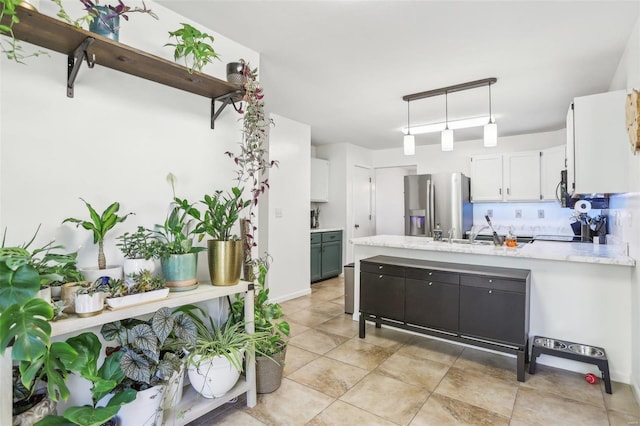 kitchen with appliances with stainless steel finishes, white cabinets, sink, and hanging light fixtures