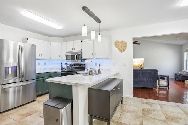 kitchen with appliances with stainless steel finishes, kitchen peninsula, white cabinetry, and light wood-type flooring