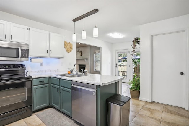 kitchen with appliances with stainless steel finishes, kitchen peninsula, white cabinetry, and decorative light fixtures