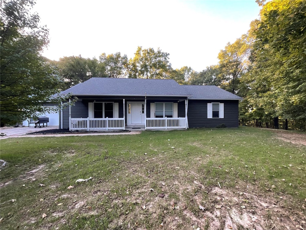 single story home featuring a front yard, a porch, and a garage