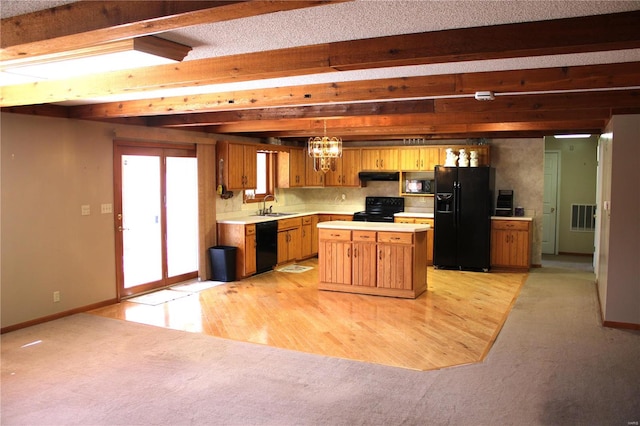 kitchen with beam ceiling, light hardwood / wood-style flooring, black appliances, a center island, and decorative light fixtures