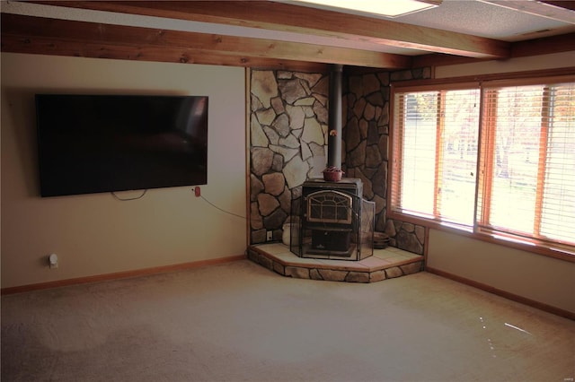 unfurnished living room featuring beamed ceiling, carpet, a textured ceiling, and a wood stove