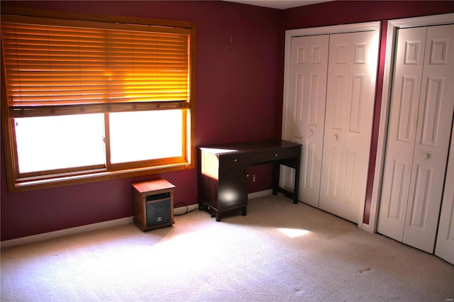 unfurnished bedroom featuring light carpet and multiple closets