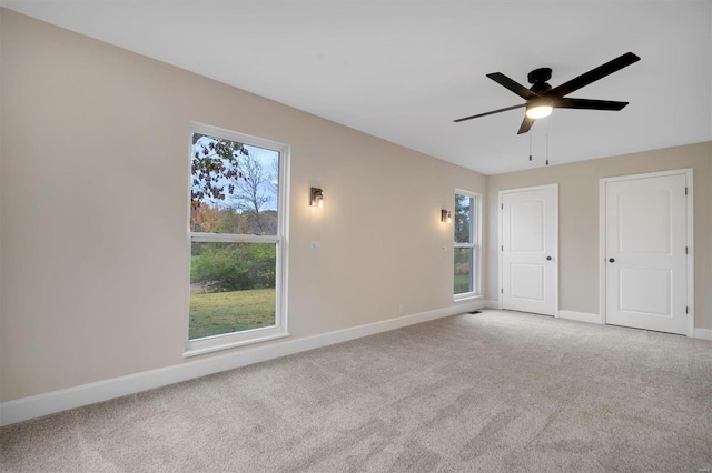 unfurnished bedroom with light colored carpet, multiple windows, and ceiling fan