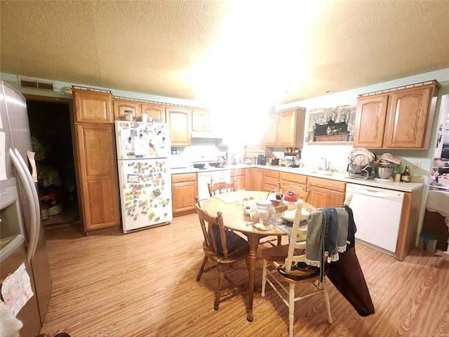 kitchen with sink, light hardwood / wood-style floors, a textured ceiling, and white appliances