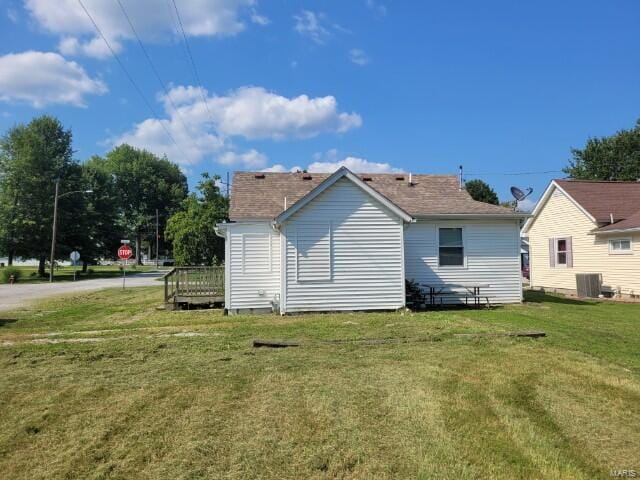 back of house featuring central air condition unit and a lawn