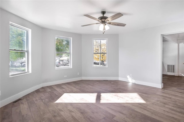 empty room with ceiling fan, a healthy amount of sunlight, and hardwood / wood-style floors