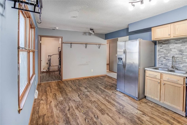 kitchen with hardwood / wood-style flooring, stainless steel refrigerator with ice dispenser, sink, light brown cabinetry, and tasteful backsplash