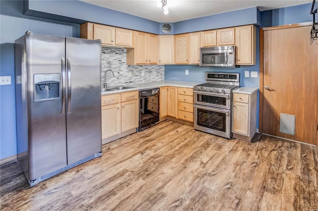 kitchen featuring light brown cabinetry, appliances with stainless steel finishes, sink, a textured ceiling, and light hardwood / wood-style flooring