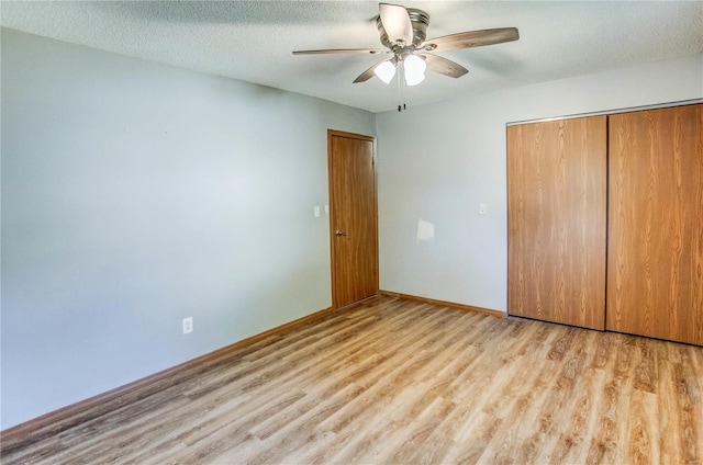 unfurnished bedroom featuring a closet, a textured ceiling, light wood-type flooring, and ceiling fan