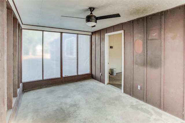 unfurnished bedroom featuring wood walls and ceiling fan