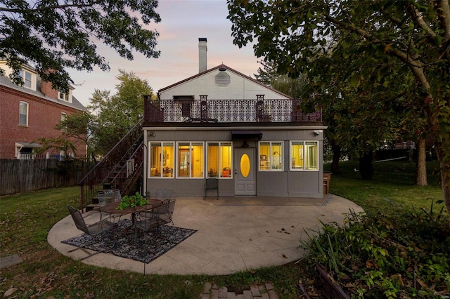 back house at dusk featuring a yard and a patio