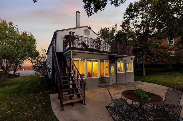 back house at dusk with a patio and a yard