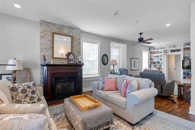 living room featuring ceiling fan, dark hardwood / wood-style flooring, and a fireplace