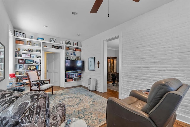 living room with hardwood / wood-style flooring, built in features, and ceiling fan