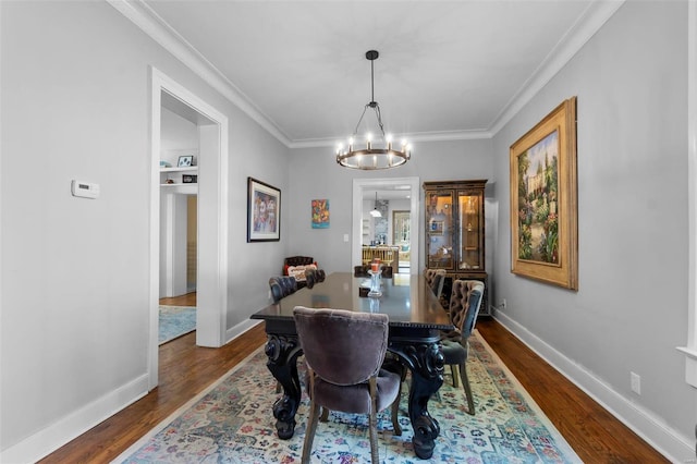 dining space featuring dark wood-type flooring, crown molding, and a notable chandelier