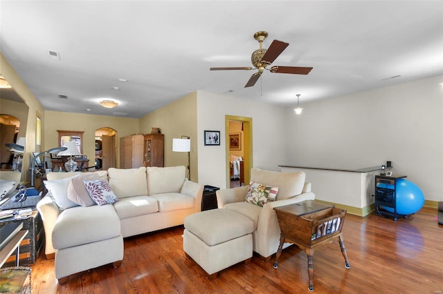 living room with dark wood-type flooring and ceiling fan