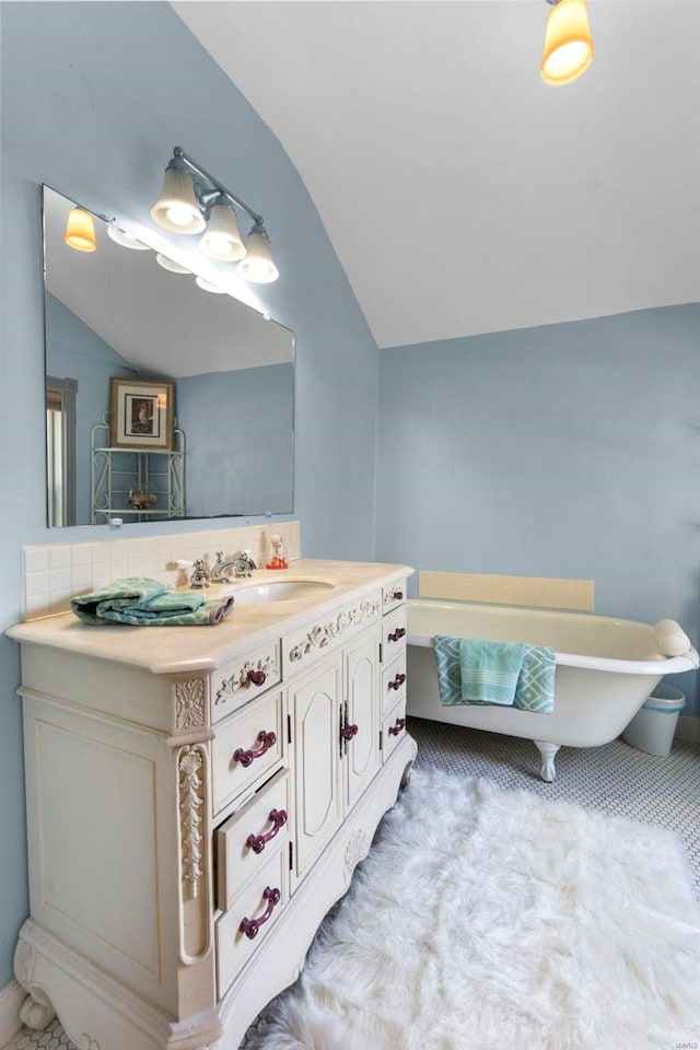 bathroom featuring vanity, vaulted ceiling, and a bath