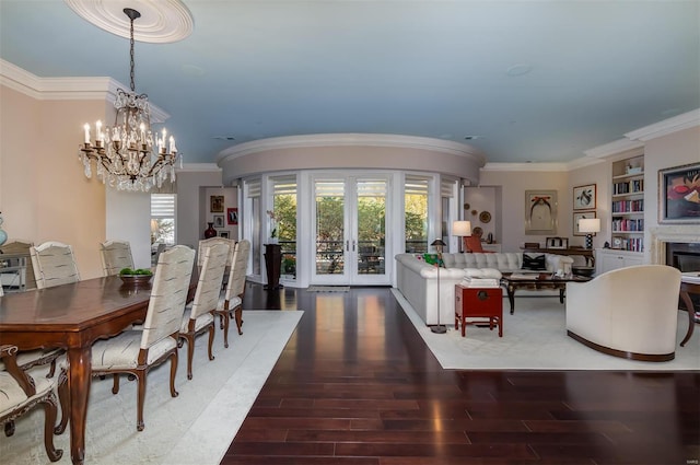 dining space featuring dark hardwood / wood-style flooring, an inviting chandelier, crown molding, built in shelves, and french doors