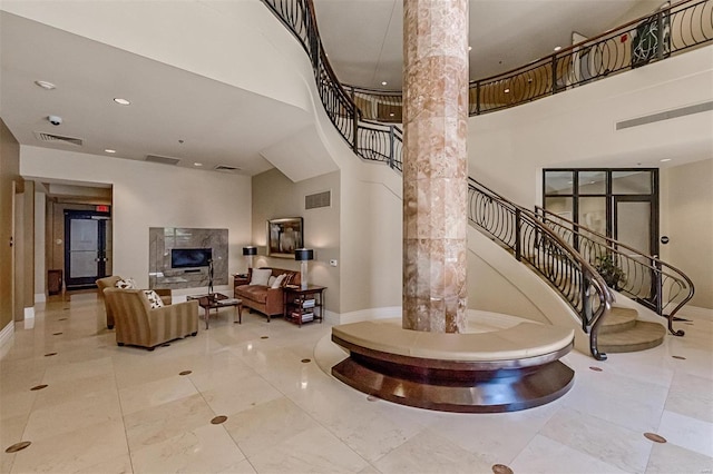 staircase with a towering ceiling, a fireplace, and decorative columns