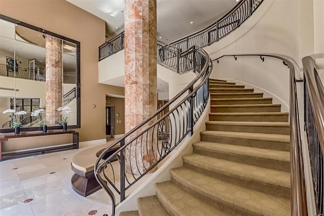 stairs featuring decorative columns and a towering ceiling