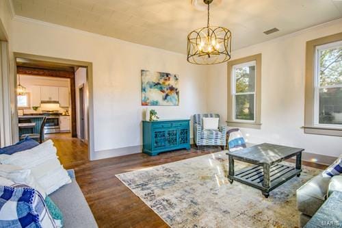 living room featuring dark wood-type flooring, ornamental molding, and a chandelier