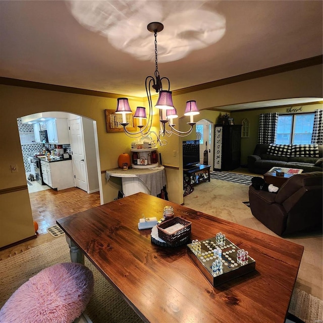 dining space featuring light hardwood / wood-style flooring, ornamental molding, and a notable chandelier