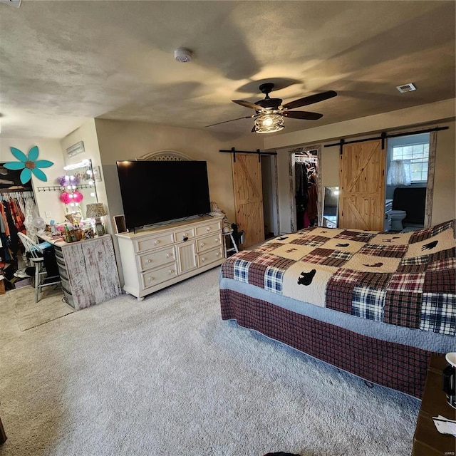 carpeted bedroom with a textured ceiling, a barn door, a closet, and ceiling fan