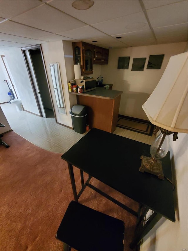 interior space featuring a paneled ceiling and light colored carpet