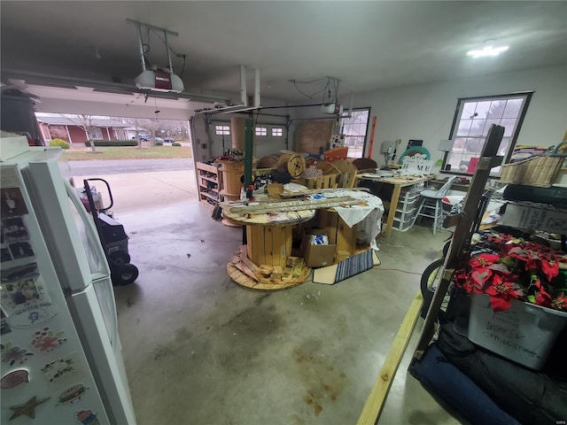 garage featuring a workshop area, white fridge, and a garage door opener