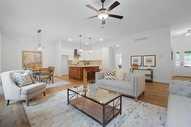 living room with sink, light hardwood / wood-style flooring, and ceiling fan