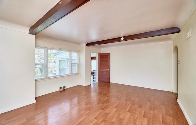 spare room featuring beam ceiling and light hardwood / wood-style floors