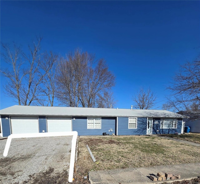 ranch-style house with an attached garage, gravel driveway, and a front yard