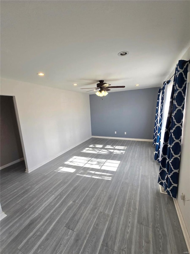 empty room featuring baseboards, wood finished floors, and a ceiling fan