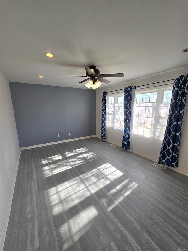 unfurnished room with a wealth of natural light, baseboards, and wood finished floors