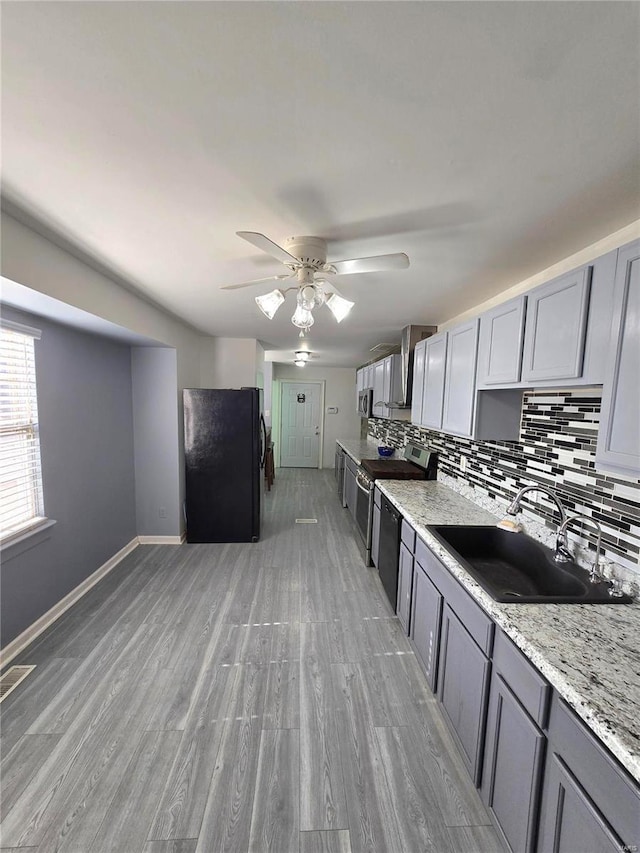 kitchen with stainless steel electric range, gray cabinets, freestanding refrigerator, and a sink