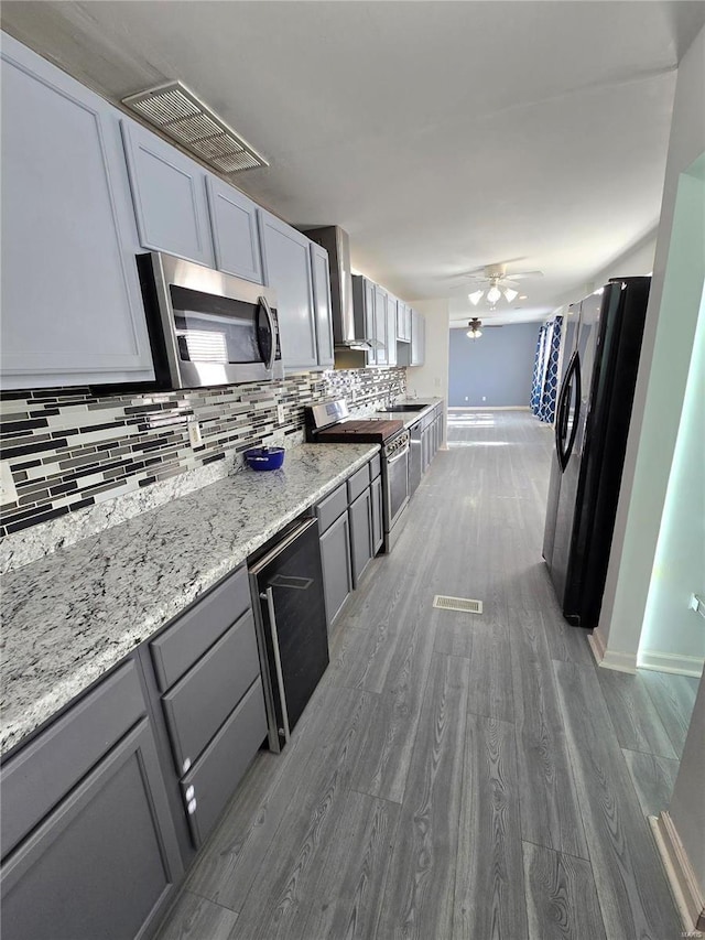 kitchen featuring tasteful backsplash, visible vents, light wood finished floors, ceiling fan, and stainless steel appliances