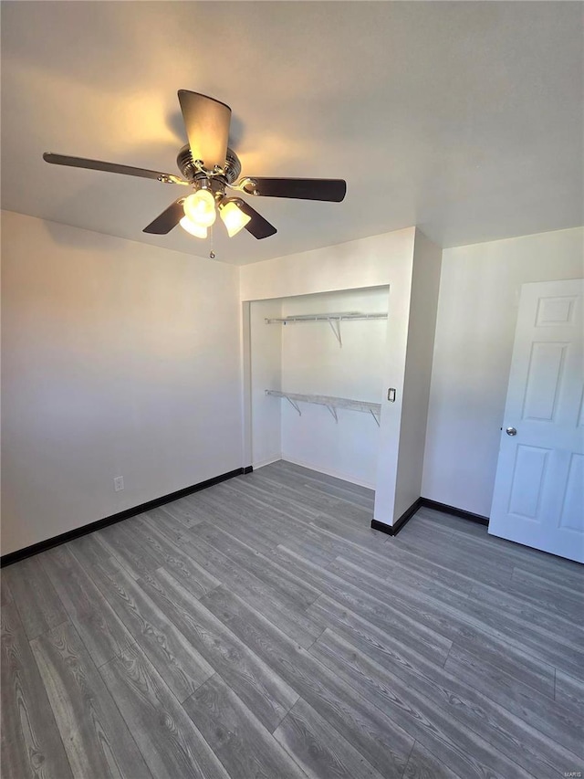 unfurnished bedroom with ceiling fan, a closet, baseboards, and wood finished floors